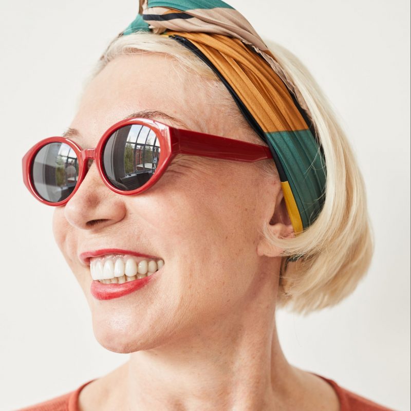 Portrait of fashion mature woman in stylish sunglasses smiling against the white background